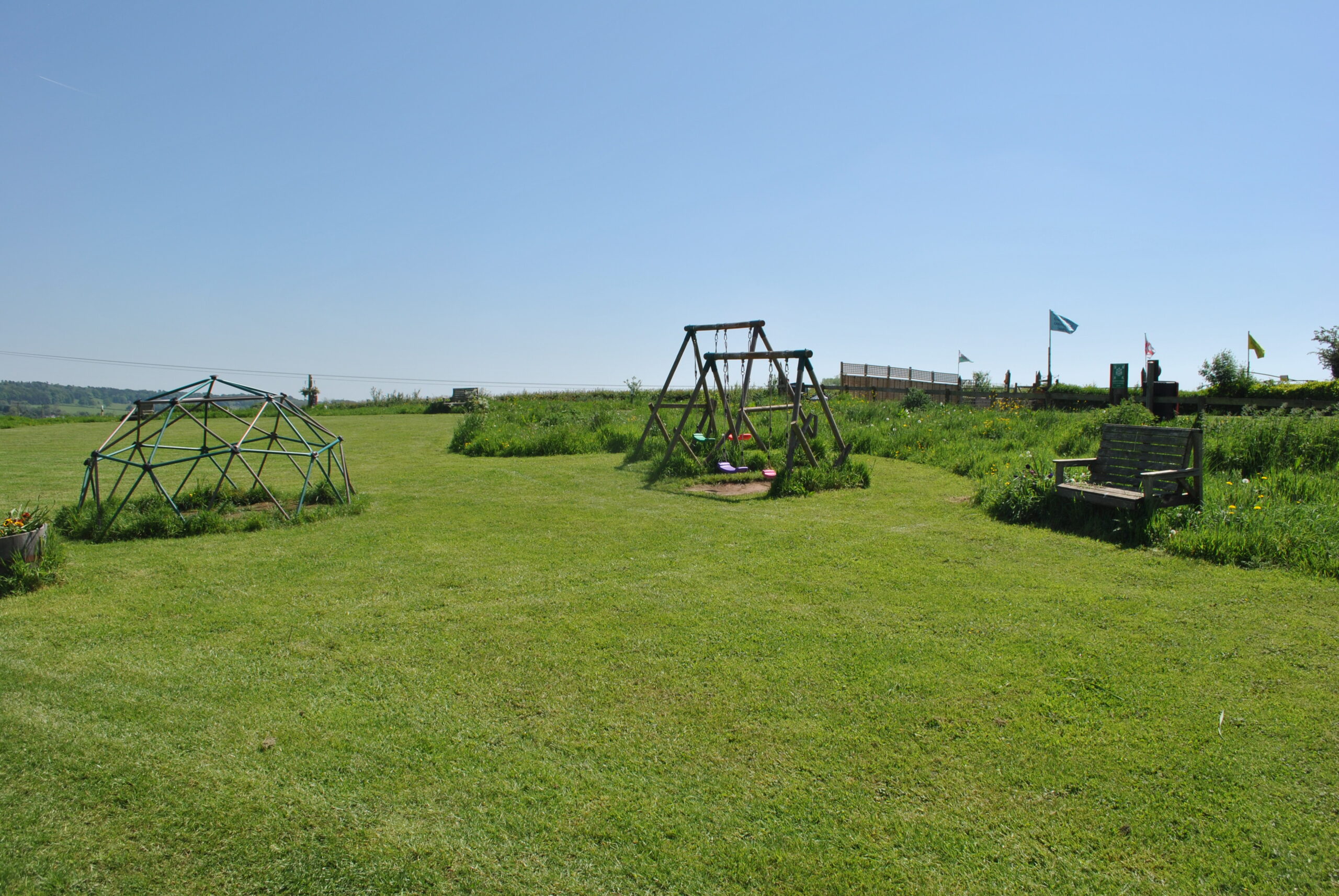 Swings, climbing frame and an open green area
